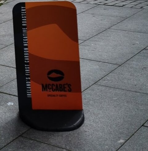 An orange and black McCabe's Specialty Coffee pavement sign