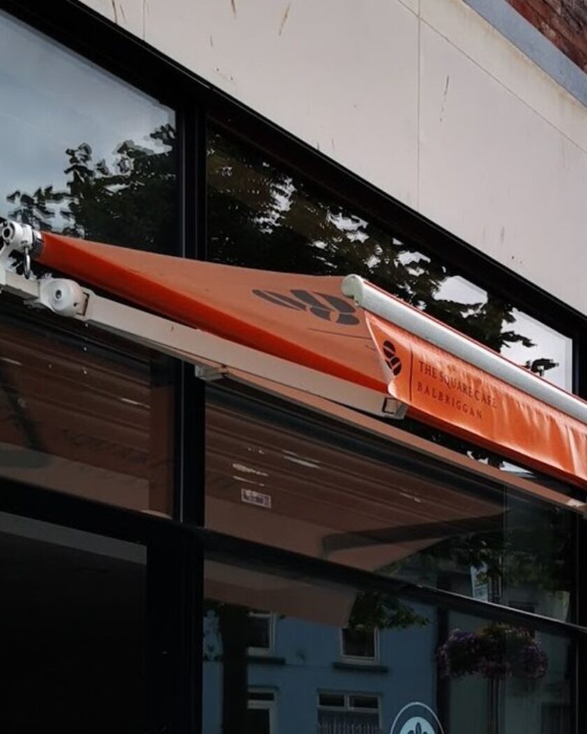 The cafe's shopfront with an orange awning and the round Square Cafe logo on the window